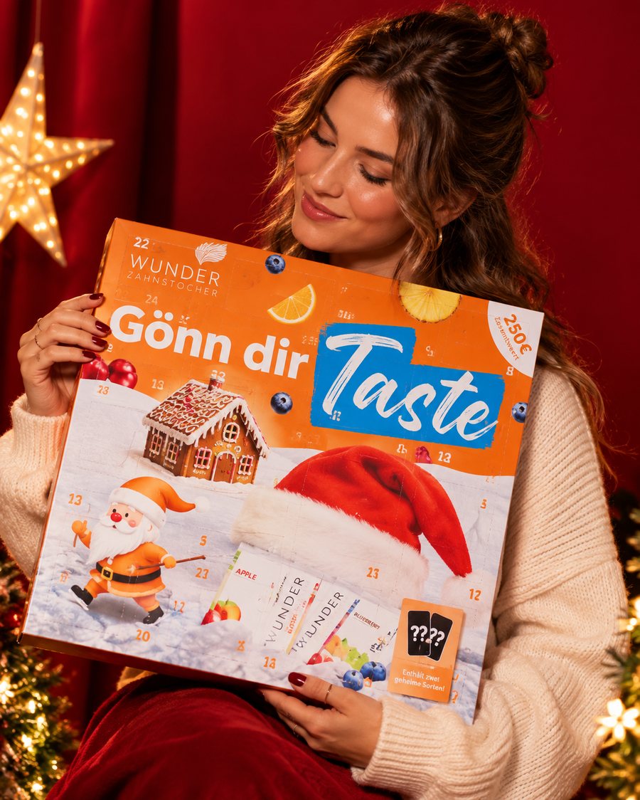 Frau hält den Wunder Adventskalender vor dem Weihnachtsbaum